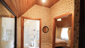 A room with wooden flooring, a bed, a wooden door, and a mirror on the wall. - Gullane East (Killarney)