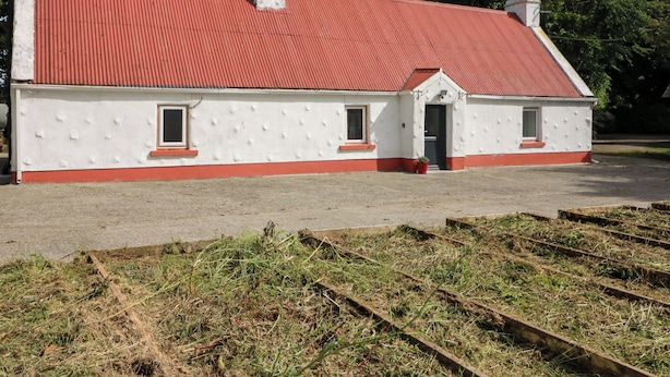 A single-story building with a red roof and white walls, featuring two windows and a door. - Gullane East (Killarney)