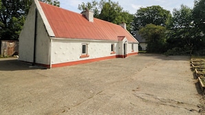 A two-story house with a red roof and white walls, a paved driveway, and a fenced yard. - Gullane East (Killarney)