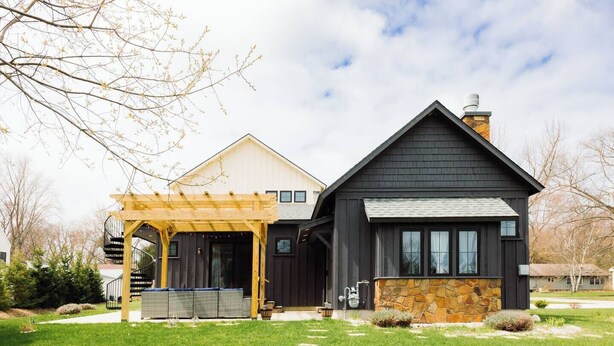 A two-story house with a covered patio, stone foundation, and a dark roof. - The Northport Sapling | In-Town Northport | Walk to Bay, Shops + Dining (Northport)