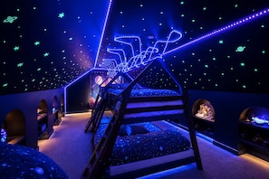 A bunk bed room with a starry ceiling and a planet mural.