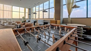 A modern hotel room with a foosball table, a sofa, a dining table, and large windows. - Margot 715 | Diseño, Confort y Ubicación Ideal (Guadalajara)