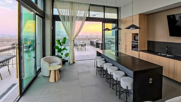 A modern kitchen with a bar area, large windows, and a view of the city. - Margot 715 | Diseño, Confort y Ubicación Ideal (Guadalajara)