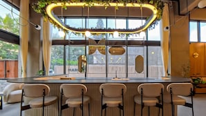 A modern bar area with a curved light fixture, bar stools, and large windows. - Margot 715 | Diseño, Confort y Ubicación Ideal (Guadalajara)