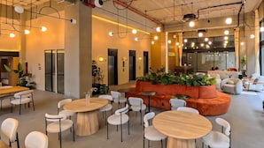 A modern interior with round tables and white chairs, a central orange sofa, and a large window. - Margot 715 | Diseño, Confort y Ubicación Ideal (Guadalajara)