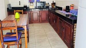 A kitchen with wooden cabinets, a dining table with chairs, a microwave, and a gas stove. - Beach house in Alemão offering comfort near the sea. House with pool, near the sea. (Caponga)