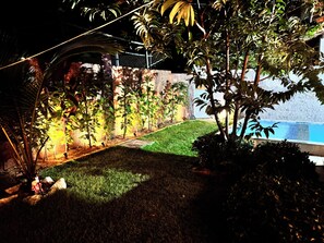 Ein gepflegter Garten mit Swimmingpool, umgeben von einer Steinmauer und unterschiedlichen Pflanzen.