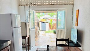 A kitchen with a refrigerator, a dining table with a green pitcher, and an open door leading to a patio. - Beach house in Alemão offering comfort near the sea. House with pool, near the sea. (Caponga)