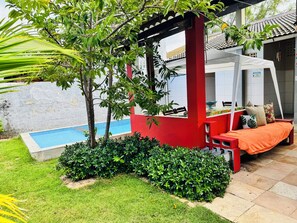 Ein Pool, eine rote Struktur und ein Bett mit Kissen.
