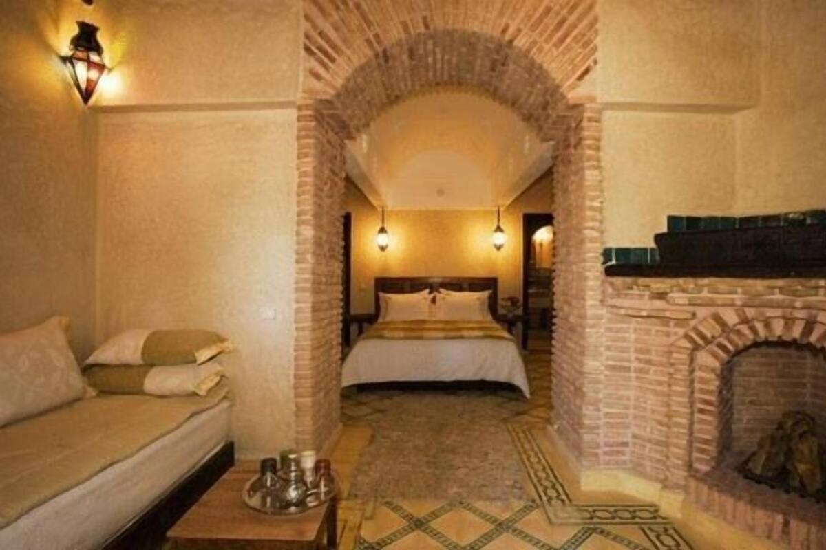 Une pièce confortable avec un lit, un canapé, une cheminée et un tapis décoratif.