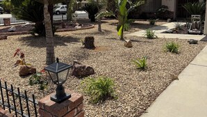 Zona residencial com jardim bem cuidado, um poste de luz e uma casa com número visível.