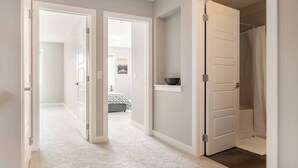 Un pasillo con puertas abiertas que dan a un dormitorio y un baño.