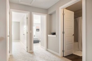 A hallway with open doors leading to a bedroom and a bathroom. - Green Bay Stay - 3BR, AC, Garage, Backyard, Self Check-in, Prof Cleaned (Calgary)