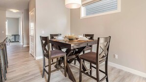 Un comedor con mesa de madera, cuatro sillas y una lámpara colgante.