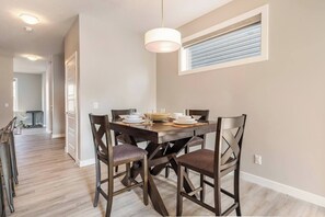 A dining area with a wooden table, four chairs, and a hanging light fixture. - Green Bay Stay - 3BR, AC, Garage, Backyard, Self Check-in, Prof Cleaned (Calgary)