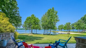 An outdoor patio with chairs and a table, overlooking a lake with trees and a clear sky. - Beautiful Waterfront Townhouse w/ Perfect Location, Fireplace & Wifi (Mineral)