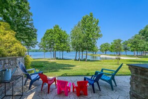 An outdoor patio with chairs and a table, overlooking a lake with trees and a clear sky. - Beautiful Waterfront Townhouse w/ Perfect Location, Fireplace & Wifi (Mineral)