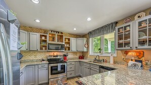 A modern kitchen with granite countertops, stainless steel appliances, and a brick backsplash. - Beautiful Waterfront Townhouse w/ Perfect Location, Fireplace & Wifi (Mineral)