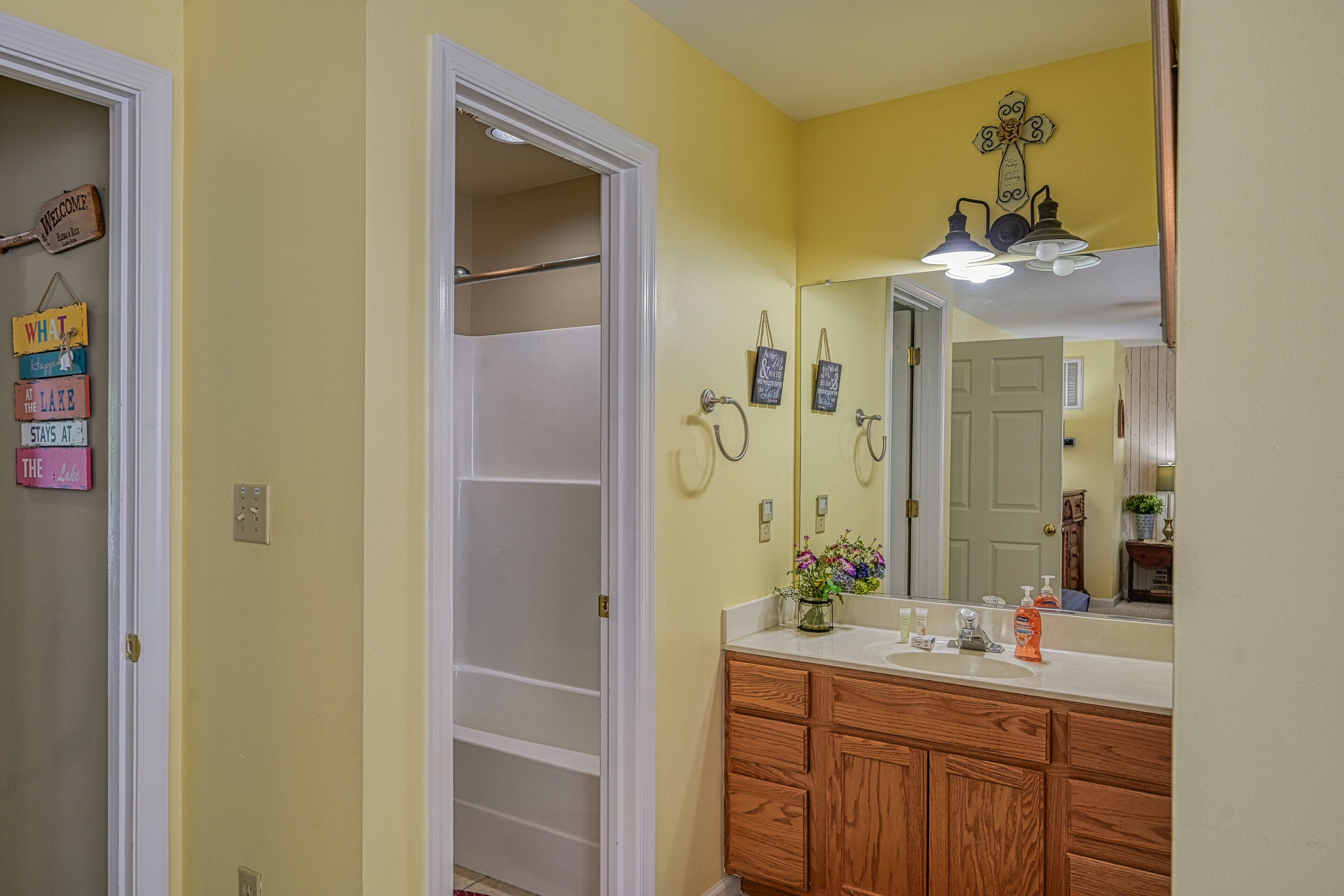 A bathroom with a wooden vanity, a mirror, and a towel rack.