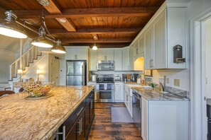 A kitchen with wooden beams, a granite countertop, stainless steel appliances, and a bowl of fruit on the island. - Beautiful Lakefront Home With Fireplace, Deck, Central AC, & Washer/dryer (Mineral)