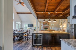 Un'ampia cucina con un'isola grande, travi in legno al soffitto e elettrodomestici moderni.