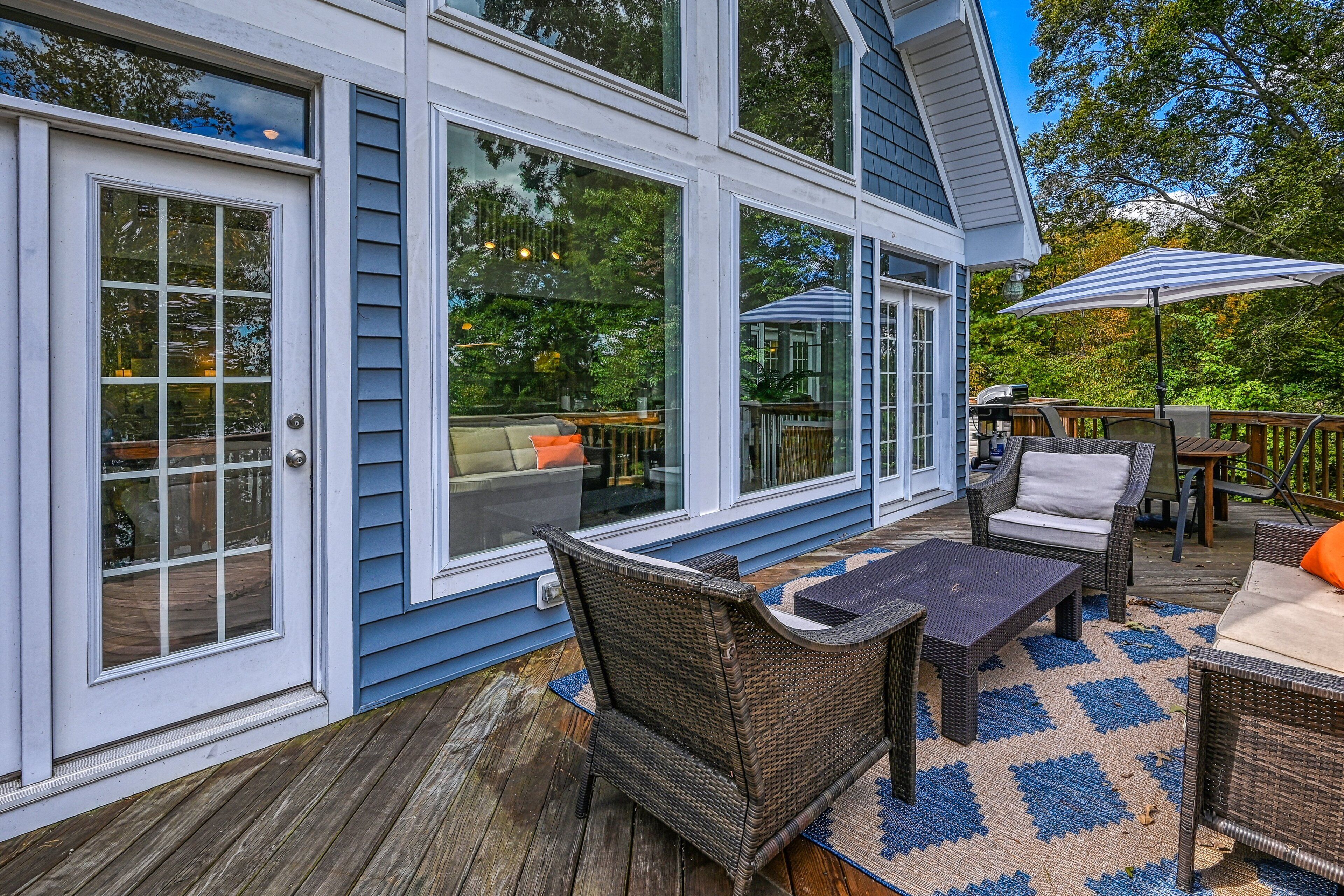 A covered deck with wicker furniture, a dining table, and a large umbrella.
