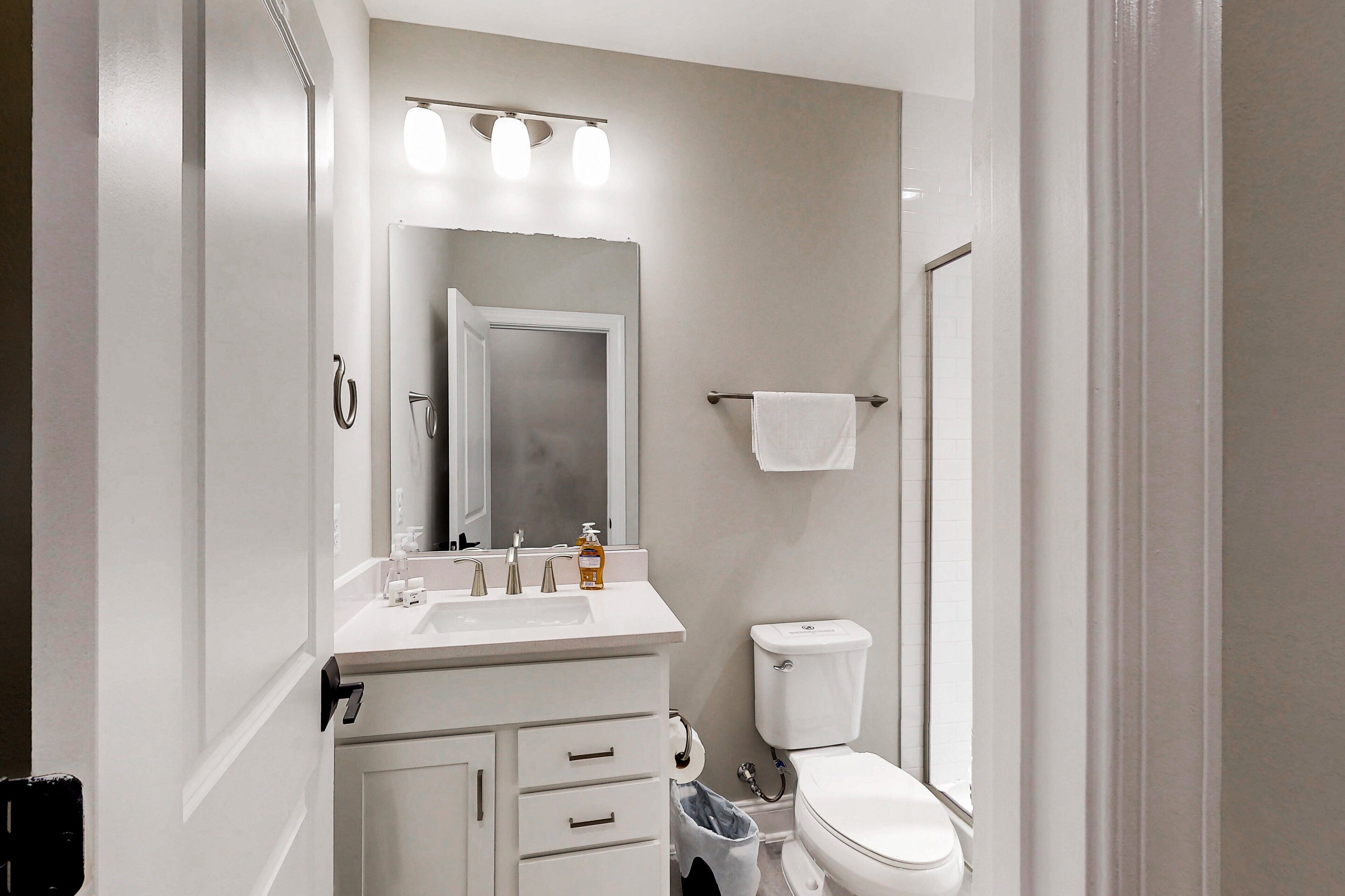 A bathroom with a white sink, mirror, and toilet.