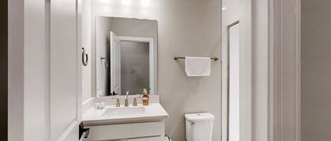 A bathroom with a white sink, mirror, and toilet.