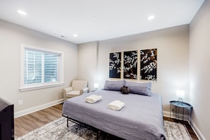 A bedroom with a bed, a chair, a nightstand, and artwork on the wall. - Charming Lakefront Retreat With Game Room and Covered Dock Access (Mineral)