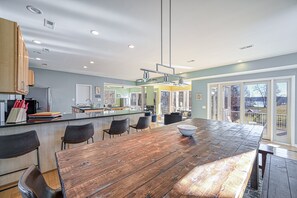 Eine moderne Küche mit einer Holztheke, einer Bar und einem großen Fenster mit Blick auf eine Terrasse.