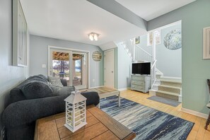 Ein Wohnzimmer mit einer Couch, einem Couchtisch, einem Fernseher und einer Treppe, die auf einen Balkon führt.