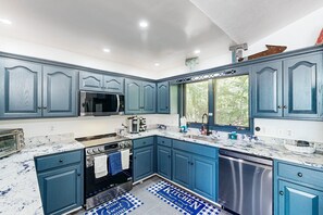 A kitchen with blue cabinets, a stove, a microwave, and a dishwasher. - Lakefront Home With two Kitchens, a Dock, Firepit, & Pontoon (Bumpass)