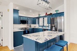 A modern kitchen with blue cabinetry, a large island, stainless steel appliances, and a pendant light. - Lakefront Home With two Kitchens, a Dock, Firepit, & Pontoon (Bumpass)