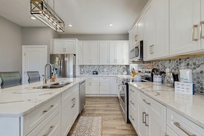 A modern kitchen with white cabinetry, a marble countertop, and a backsplash with a geometric pattern. - Charming Dog-friendly Lakefront Villa With Private Dock, Firepit, Stunning Views (Orange)