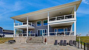 A two-story building with a balcony, stone steps, and outdoor seating.