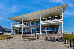 A two-story building with a balcony, stone steps, and outdoor seating. - Charming Dog-friendly Lakefront Villa With Private Dock, Firepit, Stunning Views (Orange)