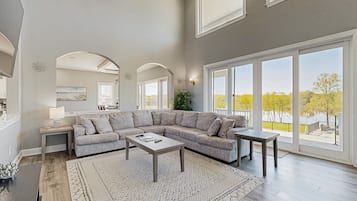 A spacious living room with a sectional sofa, a coffee table, and a view through large sliding glass doors.