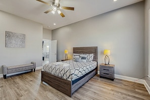 A bedroom with a bed, bedside tables, a bench, a ceiling fan, and a wall art piece. - Charming Dog-friendly Lakefront Villa With Private Dock, Firepit, Stunning Views (Orange)