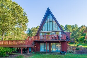 Una casa de dos pisos con un techo triangular destacado, un balcón y una terraza.