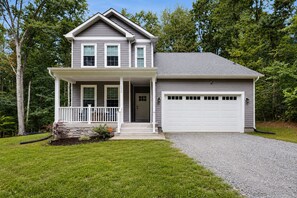 A two-story house with a front porch, a garage, and a driveway. - Cozy Retreat With Forest Views, Peaceful Vibes & Modern Comfort (Bumpass)