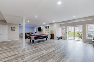 Una habitación amplia con mesa de billar, sofá y televisión.