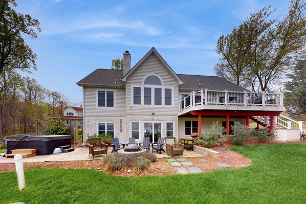 A two-story house with a covered patio, a hot tub, and a fire pit. - Dog-friendly Lake Luxury With dry Sauna, hot Tub, Game Room (Bumpass)