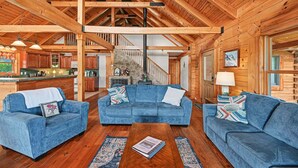 A log cabin interior with a living area featuring blue sofas, a coffee table, and a fireplace. - Dog-friendly, Lake View Cabin w/ Furnished Decks, Ping-pong & Darts (Louisa)