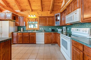 Une cuisine avec des meubles de rangement en bois, un réfrigérateur blanc, une cuisinière, un four à micro-ondes et un lave-vaisselle.