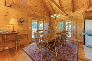 A wooden interior with a dining table surrounded by chairs, a chandelier, and a refrigerator. - Dog-friendly, Lake View Cabin w/ Furnished Decks, Ping-pong & Darts (Louisa)