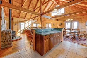 A spacious kitchen with wooden beams, a large island, and a dining area with chairs. - Dog-friendly, Lake View Cabin w/ Furnished Decks, Ping-pong & Darts (Louisa)