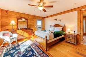 A wooden-paneled bedroom with a bed, dresser, chair, and a ceiling fan. - Dog-friendly, Lake View Cabin w/ Furnished Decks, Ping-pong & Darts (Louisa)