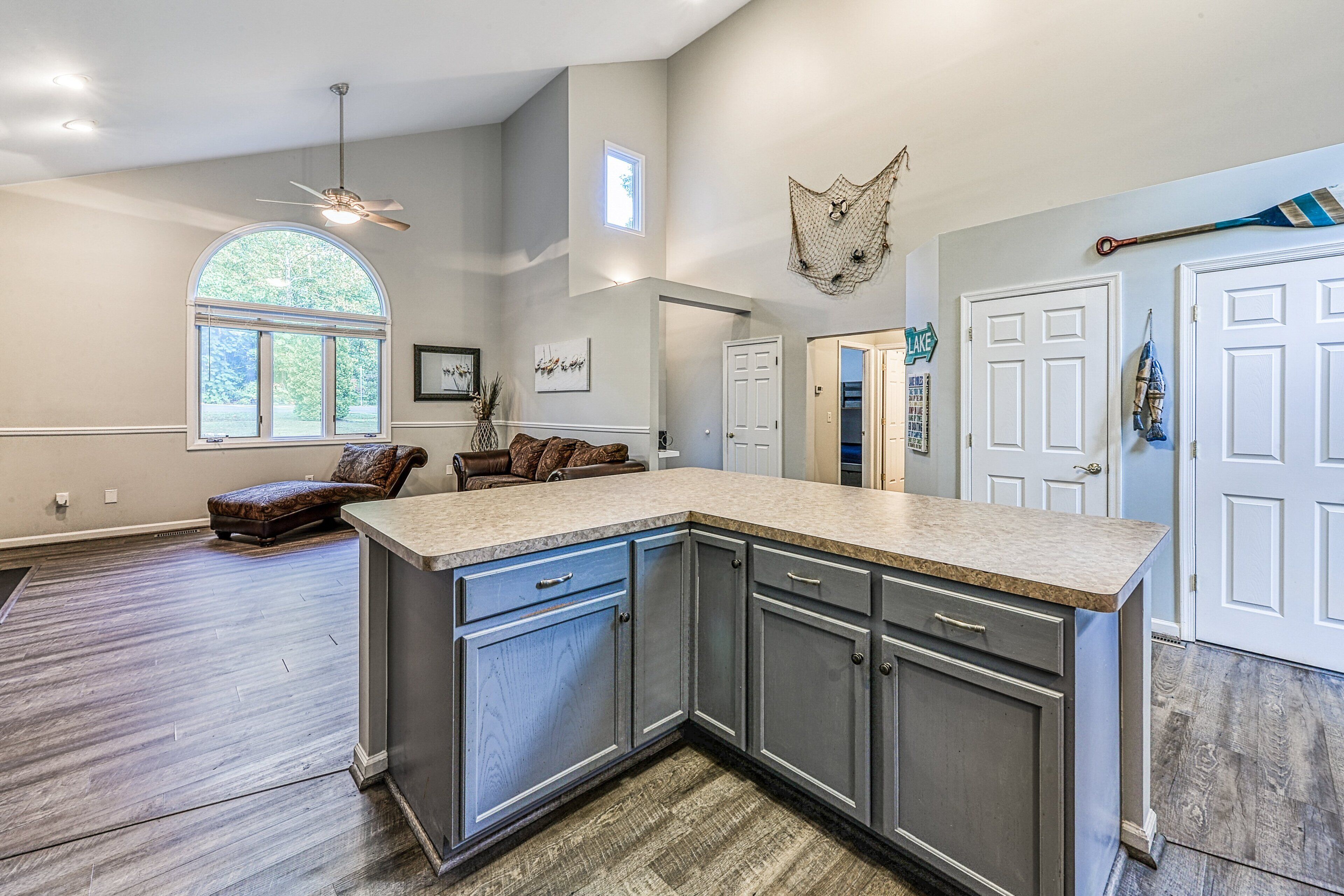 A kitchen with a large island, wooden flooring, and a ceiling fan.