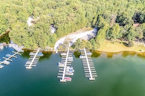 Vista aérea de un puerto deportivo con muelles y barcos, rodeado de un bosque frondoso.