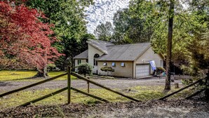 A house with a garage, surrounded by trees and a gravel driveway. - Dog-friendly Home With Free Wifi, Central AC, Firepit, & Furnished Deck (Mineral)